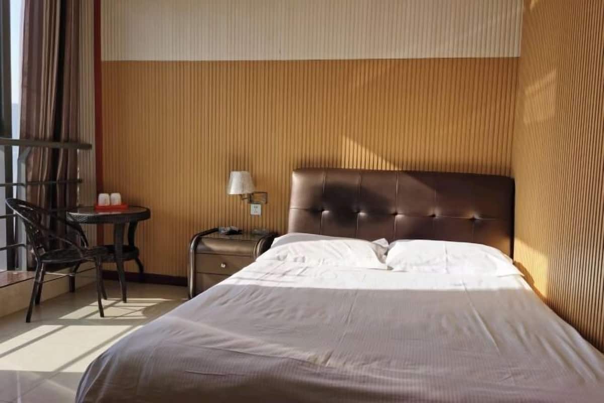 Een hotelkamer met een bed, een stoel, een tafeltje en een lamp.