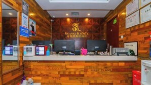 Un mostrador de recepción de hotel con diseño de pared de madera, un logotipo grande y múltiples monitores.