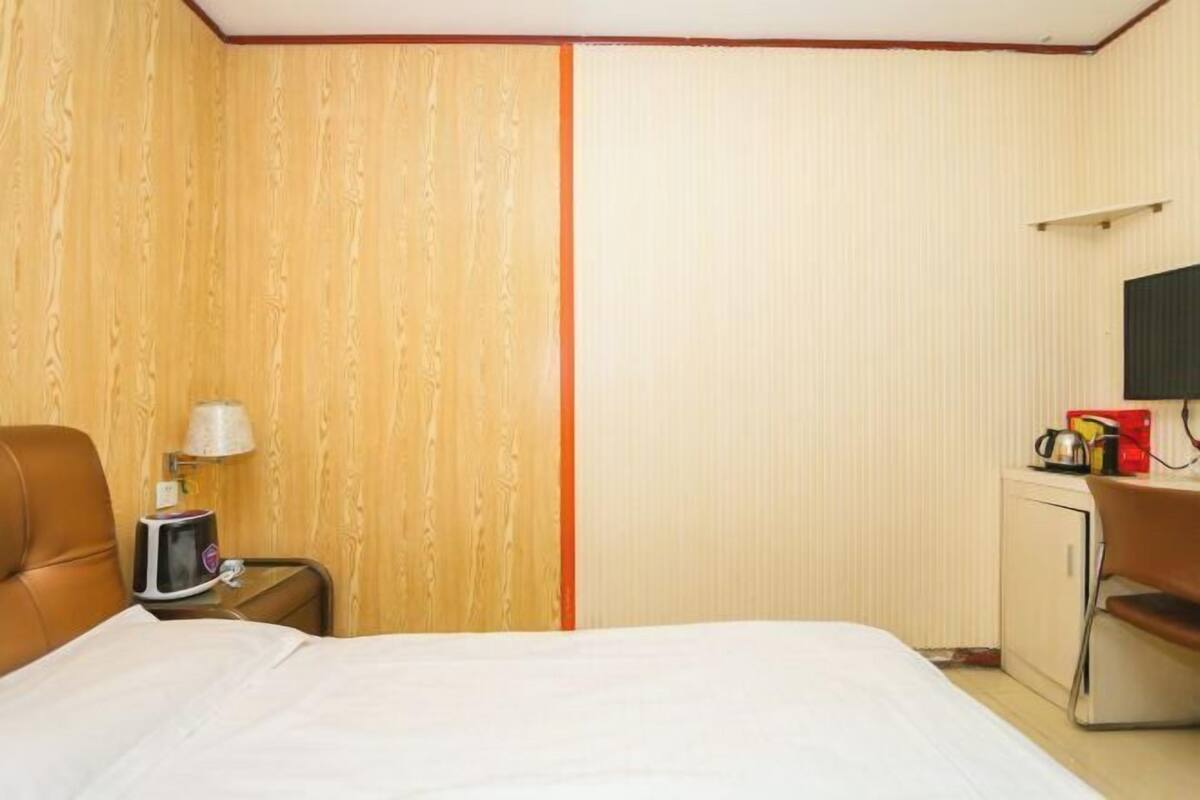 Een hotelkamer met een bed, een bureau, een stoel, een lamp en een televisie.