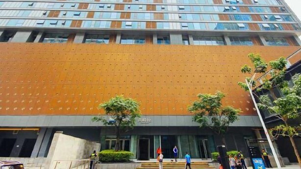 Un edificio moderno con un amplio ventanal de vidrio y una pared naranja texturizada.