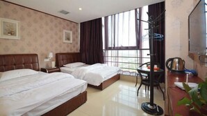 Habitación de hotel con dos camas, un escritorio con hervidor, una silla y un ventanal con cortinas.