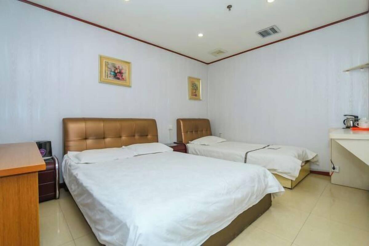 Een hotelkamer met twee bedden, een bureau en een stoel.