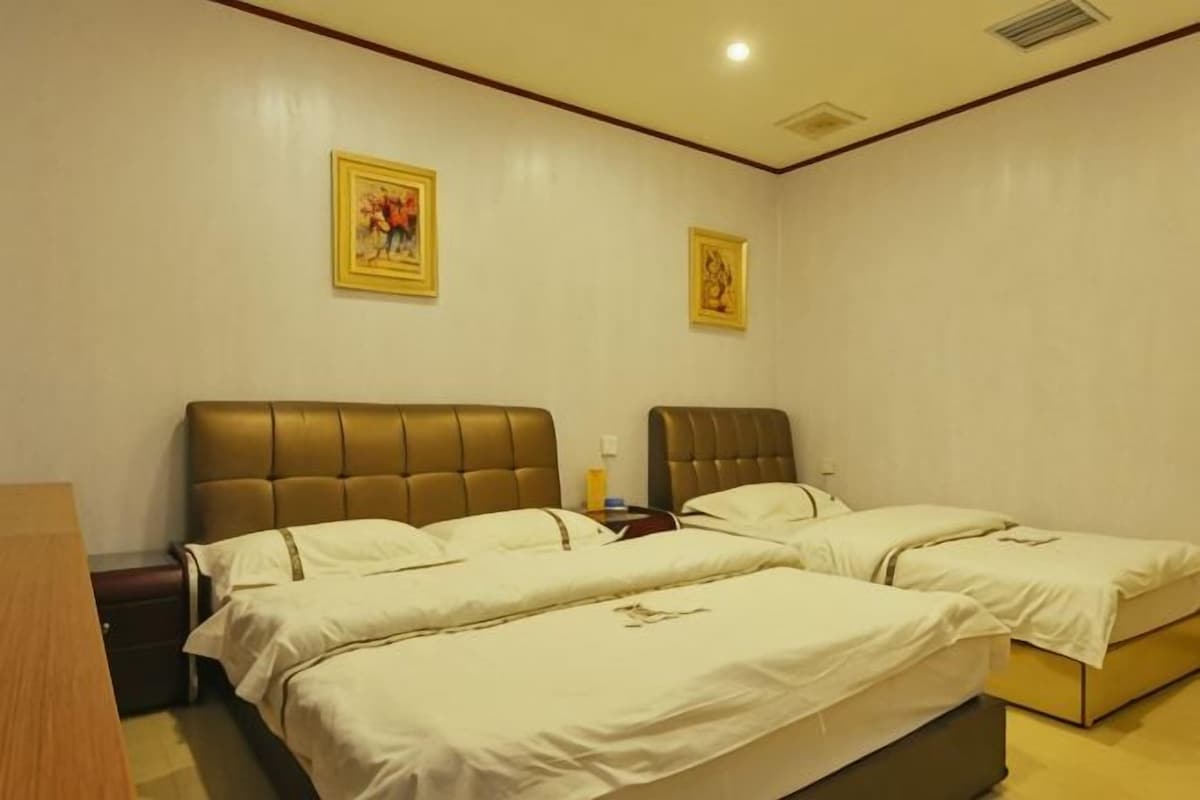 Habitación de hotel con dos camas, una mesita de noche y una lámpara fijada a la pared.