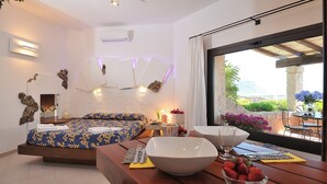 Une chambre moderne avec un grand lit, un coin repas comprenant une table et des chaises, et une vue sur l’extérieur.