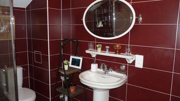 A bathroom with a white sink, a round mirror, and a shelf with toiletries.