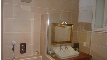 Een badkamer met een douche, een wastafel en een spiegel.