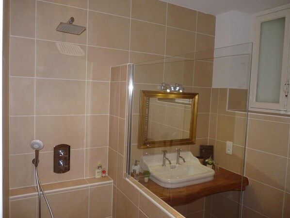 Un baño con ducha, lavamanos y espejo.