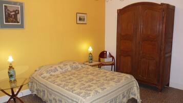 Une chambre avec un lit, deux lampes de chevet, une armoire en bois et un lustre.