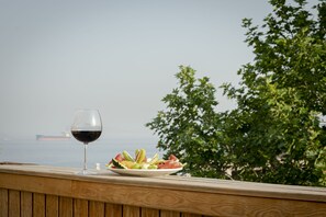A wooden deck with a glass of red wine and a plate of fruit. - Ishak Pasa Palace by Joyway Hotels (Istanbul)