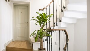 Un escalier orné d’un pot de fleurs, une porte portant le numéro 7 et un luminaire.