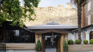 Un bâtiment en pierre avec une entrée en bois et un patio couvert.