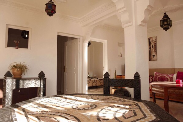 A bedroom with a bed, a nightstand, a potted plant, a mirror, and a door leading to another room. - 5 min from beach, flat 80 m² terrace ideal family/surfeur peaceful typical Berber village (Tamraght)