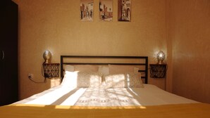 A neatly made bed with patterned pillows, a wooden headboard, and two wall-mounted lamps.