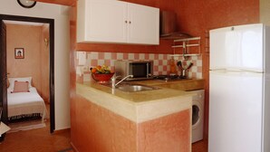 A compact kitchen with a microwave, sink, and washing machine.