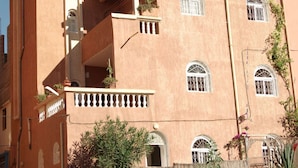 A multi-story building with balconies, arched windows, and a staircase.