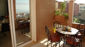 Ein Balkon mit Tisch und Stühlen, einem Blumentopf und Blick auf die Stadt.