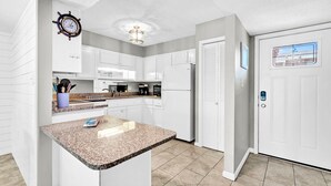 A modern kitchen with white cabinetry, a granite countertop, and a built-in oven. - Beach Service Included! Private Beach Access, Chateau La Mer 4B! (Destin)