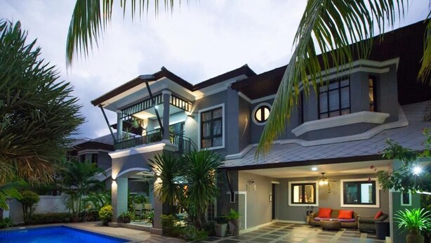 A two-story house with a swimming pool, a balcony, and a well-lit interior.