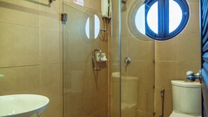 A bathroom with a glass-enclosed shower, a white sink, and a toilet.