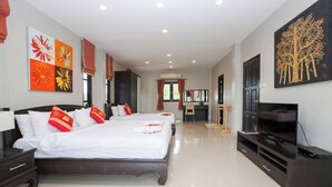 A hotel room with a large bed, a desk, a TV, and artwork on the walls.