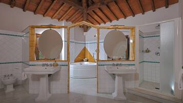 Un baño con dos lavamanos, una bañera y una ducha.