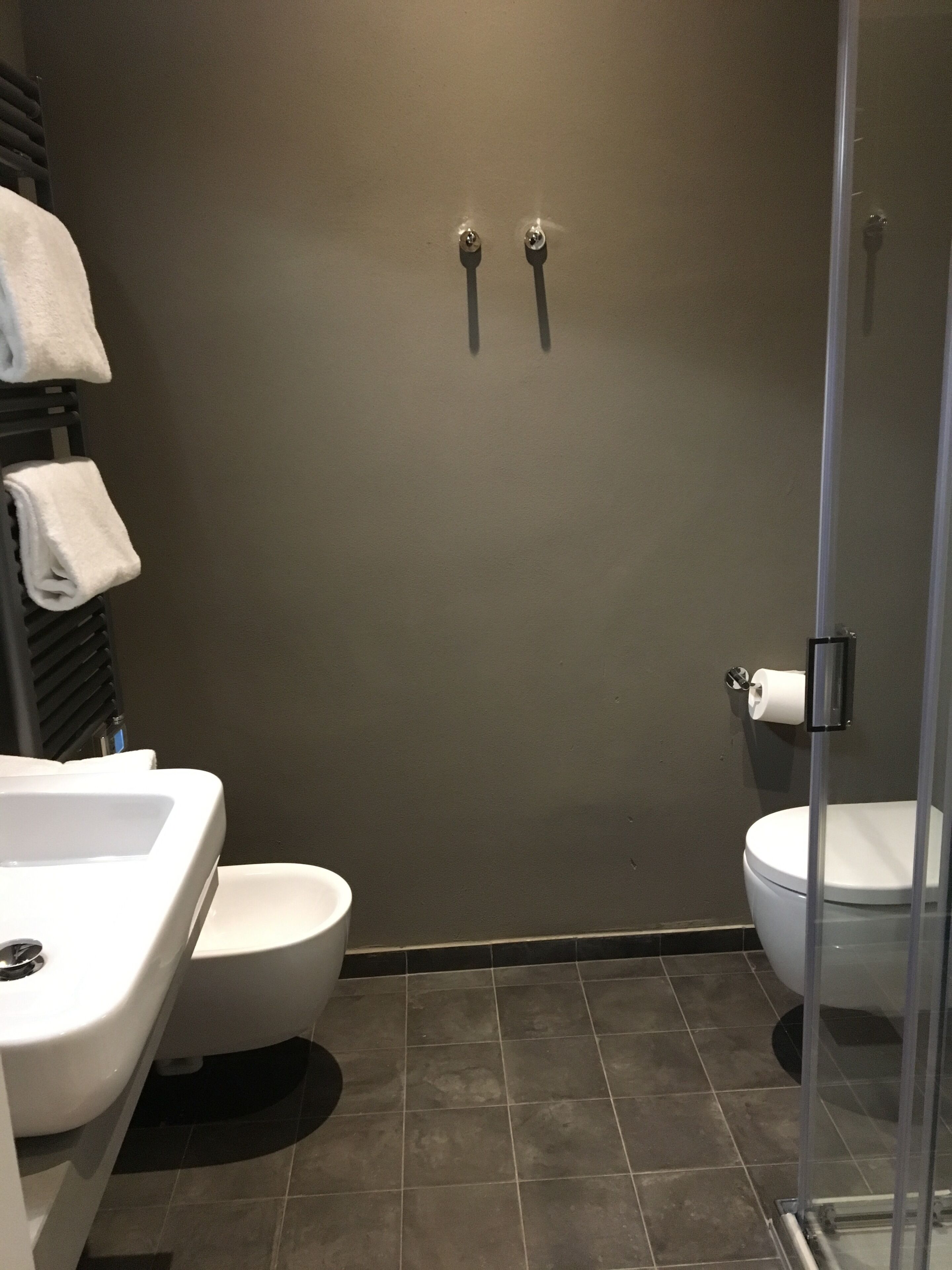 A modern bathroom with a shower enclosure, a toilet, and a sink.