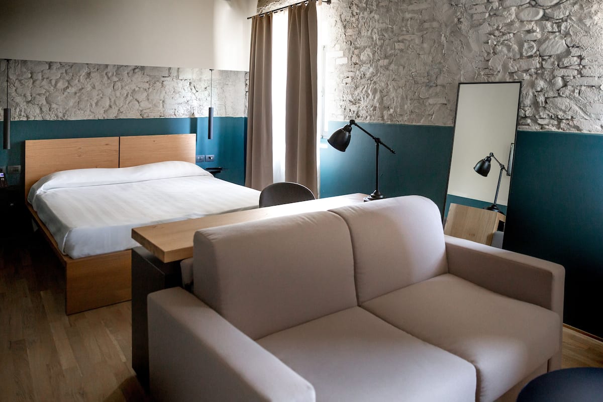 Ein Hotelzimmer mit einem Bett, einem Schlafsofa, einem Schreibtisch, einer Lampe und einem Spiegel.
