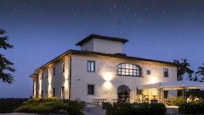 A large, two-story building with a covered outdoor seating area and a well-lit entrance. - Palagina la cascina (Figline e Incisa Valdarno)