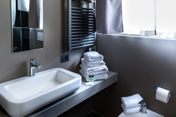 A bathroom with a sink, mirror, towel rack, and toilet paper holder.