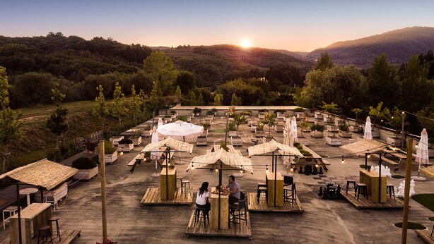 An outdoor dining area with multiple tables and umbrellas, surrounded by greenery and hills in the background. - Palagina la cascina (Figline e Incisa Valdarno)