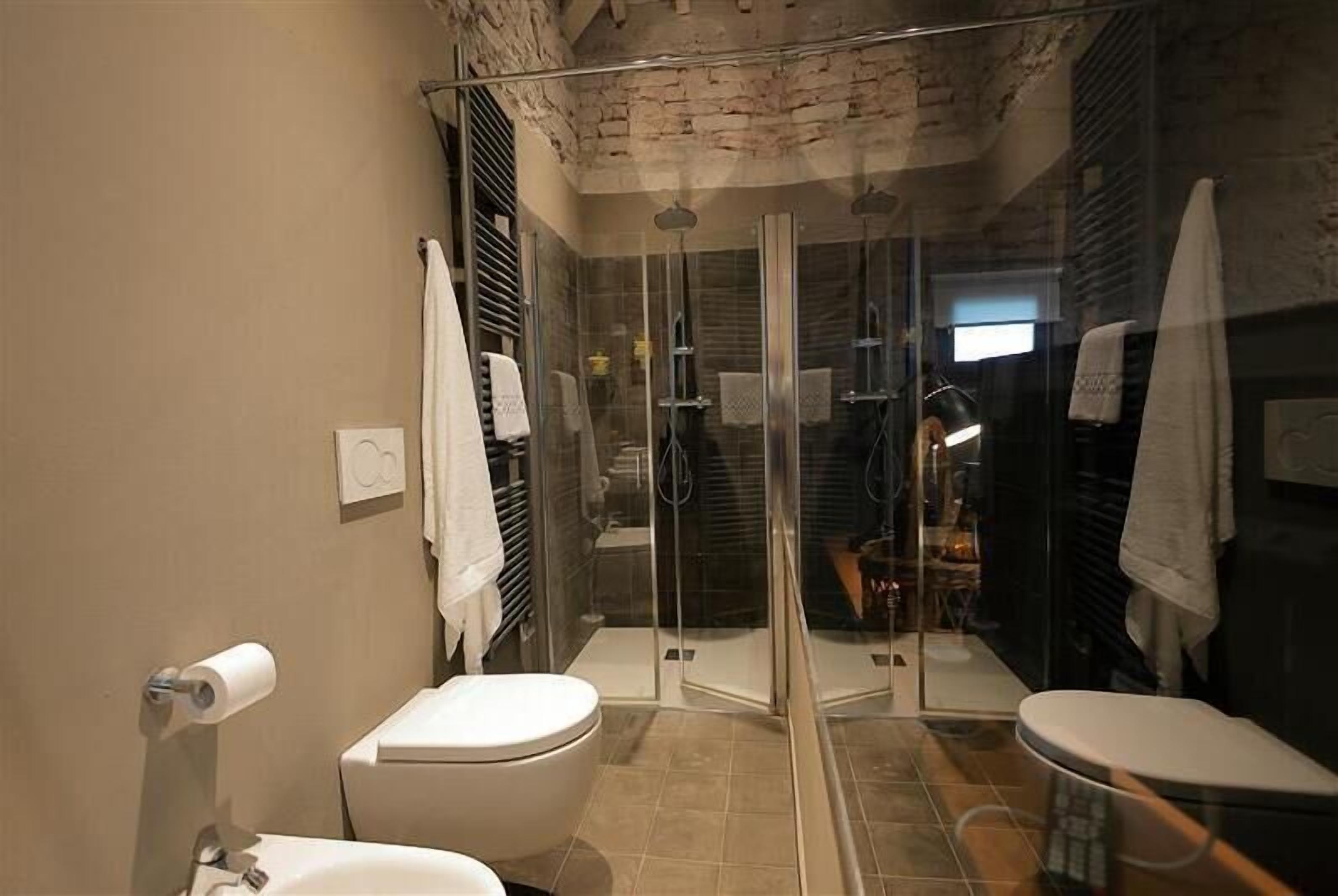 A modern bathroom with a glass-enclosed shower, a toilet, and a sink.