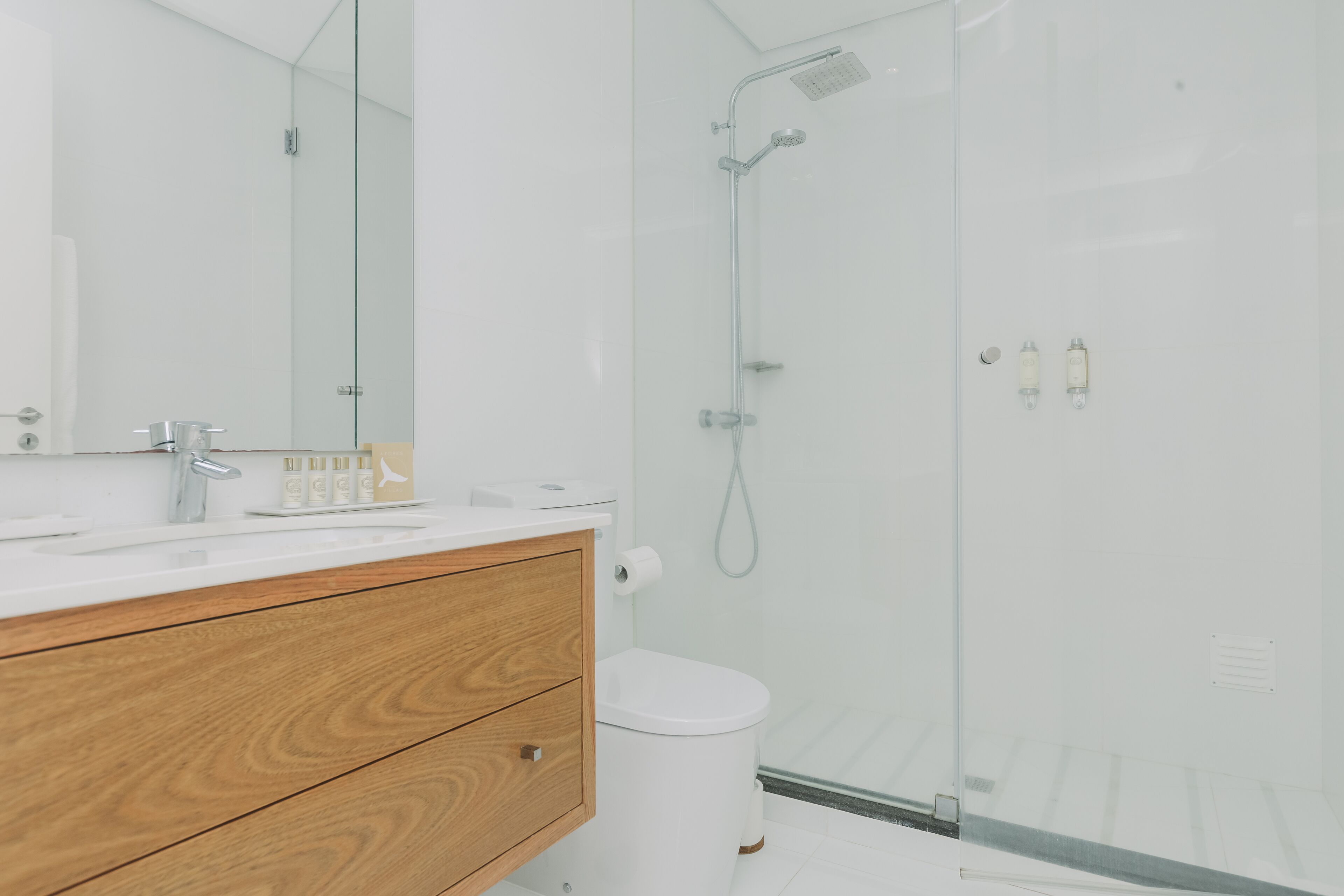 A modern bathroom with a glass shower enclosure, a wooden vanity, and a white toilet.