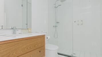 A modern bathroom with a glass shower enclosure, a wooden vanity, and a white toilet.