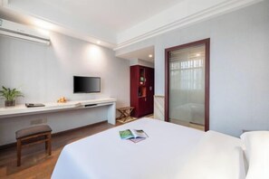 Una habitación de hotel con cama, televisión, escritorio con silla, una mesita pequeña y un armario rojo.