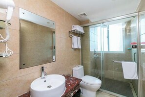 Un baño moderno con un espejo grande, un lavabo, un inodoro y una cabina de ducha con mampara de vidrio.