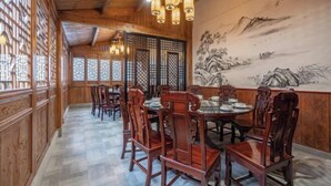 A traditional dining room with wooden furniture and a mural on the wall. - Xingji Hotel (Dongyang)