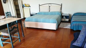 Um quarto com cama, cadeira, mesa e guarda-roupa.