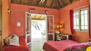 Una habitación con dos camas, techo de madera, una puerta que da al exterior y una mesa con lámpara.
