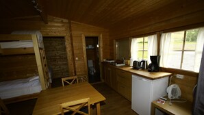 Una cabaña de madera con literas, una cocina con refrigerador y una mesa de comedor.