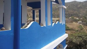 Un edificio azul y blanco con un balcón que da a un paisaje montañoso.
