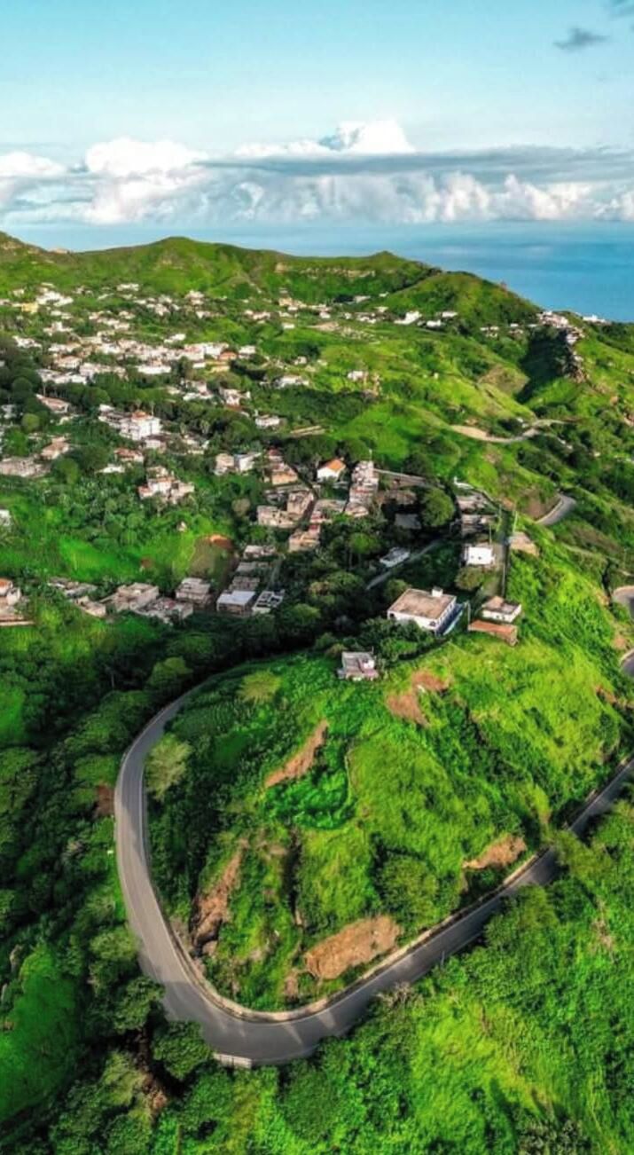 Vista aérea de un pueblo costero con carreteras sinuosas y edificios dispersos.