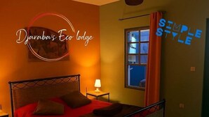 Una habitación con cama, mesita de noche, lámpara y ventana con cortinas.