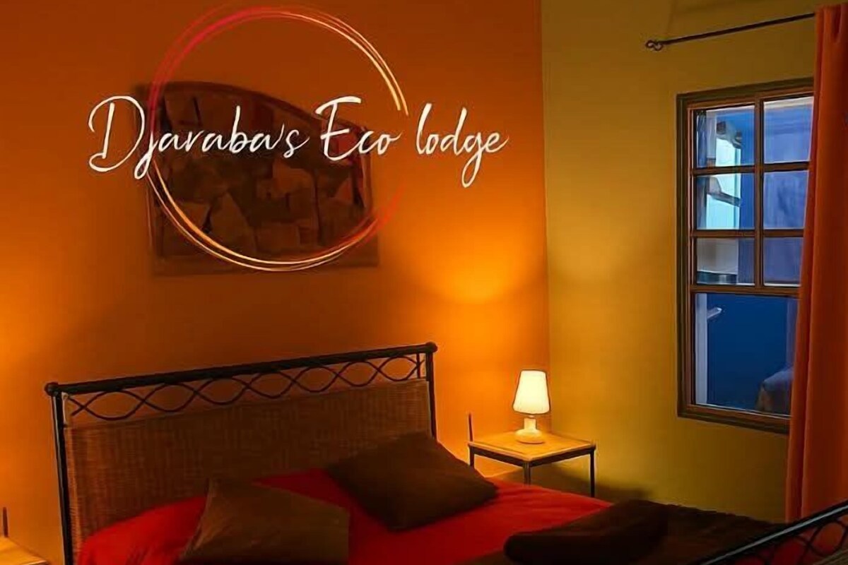 A room with a bed, a nightstand, a lamp, and a window with curtains.