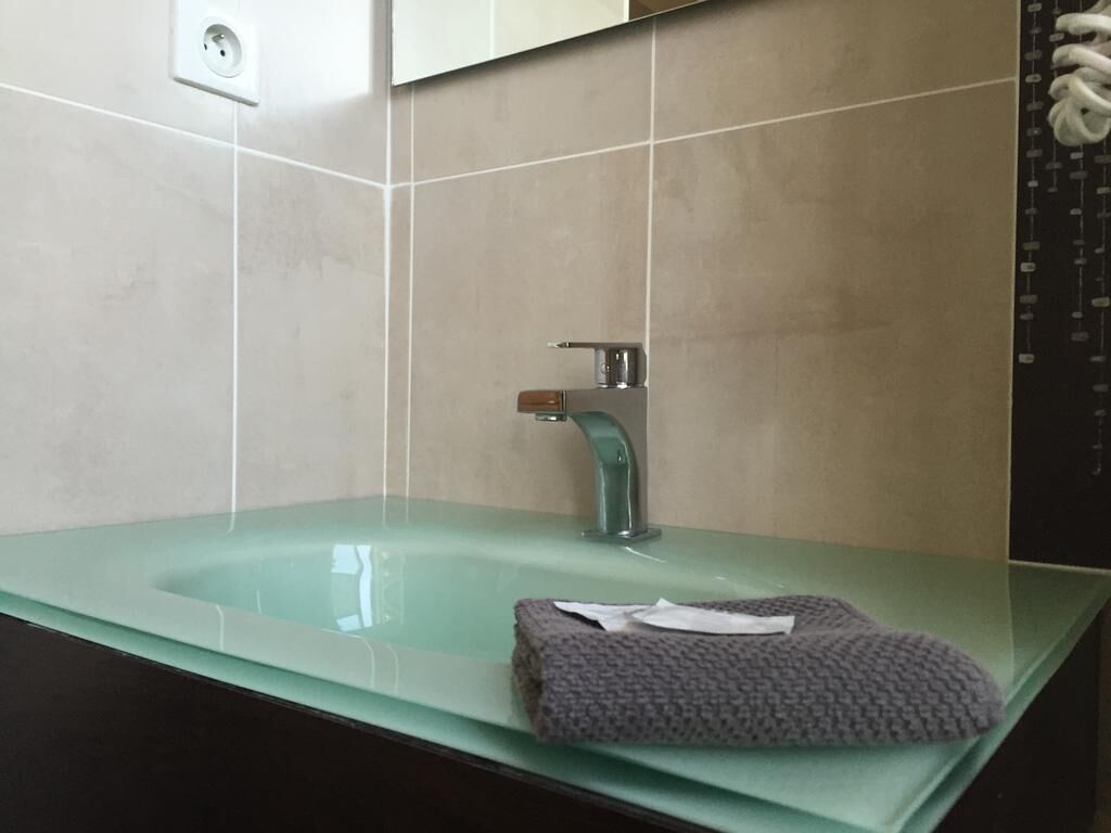 Un baño con un lavamanos de vidrio, una toalla y un espejo.