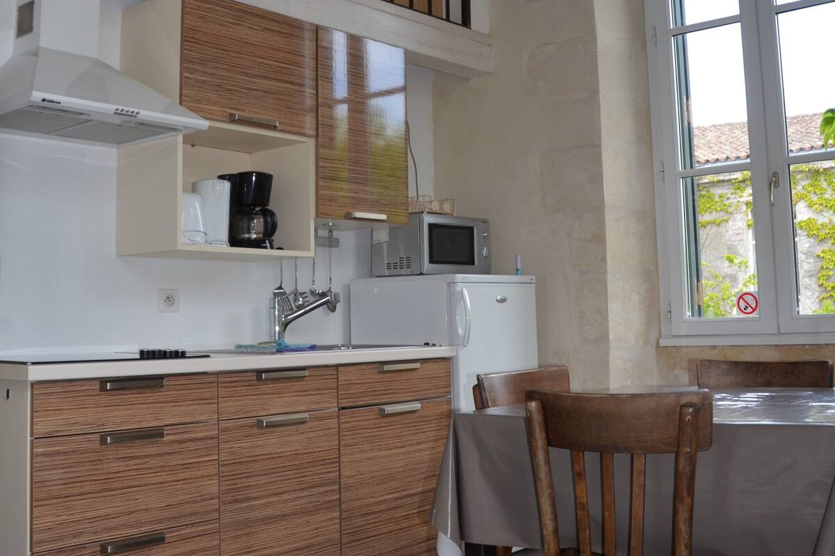 A compact kitchen with wooden cabinets, a built-in microwave, a coffee maker, and a refrigerator.