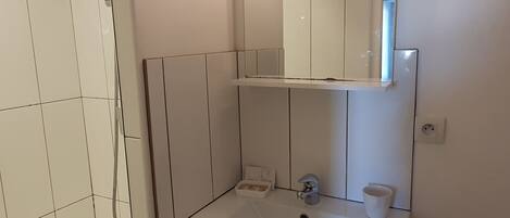 A modern bathroom with a shower, sink, and toilet.