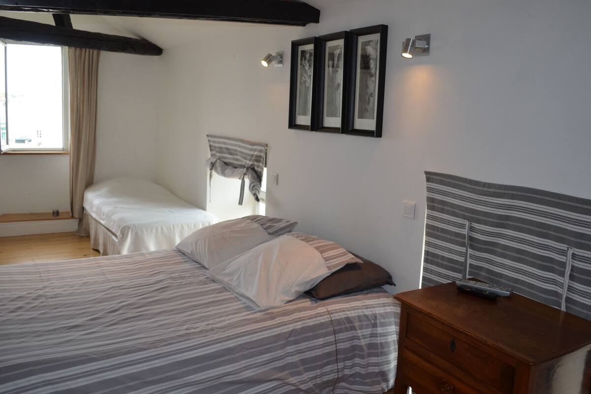 A bedroom with two beds, a wooden dresser, and a window with curtains.