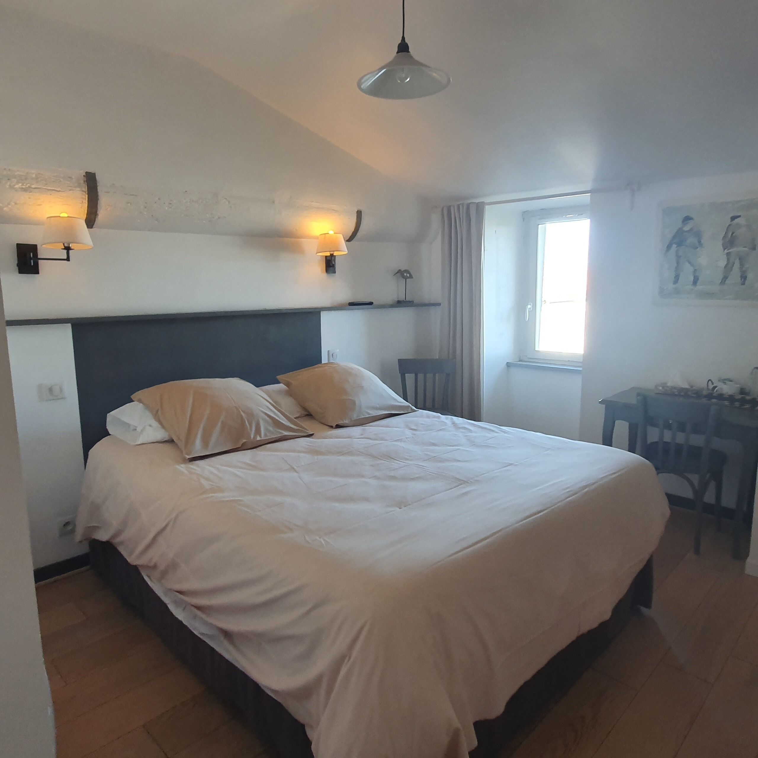 Un dormitorio con cama, lámparas de noche, un escritorio y una ventana.