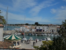 Un port de plaisance avec des bateaux amarrés, un kiosque et des bâtiments aux toits couverts de tuiles.