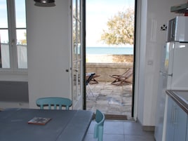 Une cuisine donnant sur la mer, avec une porte ouverte.